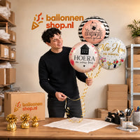 Jesse houdt Nieuw Huis Trosje Ballonnen vast in de warme werkplaats van Ballonnenshop.nl.