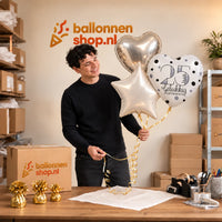 Jesse houdt 25 Jaar Getrouwd Trosje Ballonnen vast in de warme werkplaats van Ballonnenshop.nl.