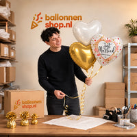 Jesse houdt Just Married Hartjes Trosje vast in de warme werkplaats van Ballonnenshop.nl.