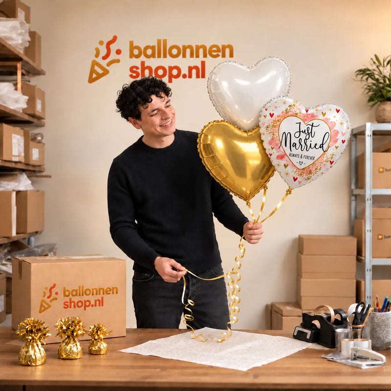 Jesse houdt Just Married Hartjes Trosje vast in de warme werkplaats van Ballonnenshop.nl.