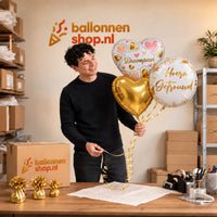 Jesse houdt Hoera Getrouwd Droompaar Trosje vast in de warme werkplaats van Ballonnenshop.nl.