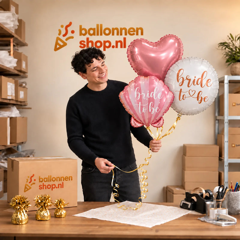 Jesse houdt Bride To Be Trosje Ballonnen vast in de warme werkplaats van Ballonnenshop.nl.