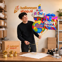 Jesse houdt Happy Birthday Trosje Ballonnen vast in de warme werkplaats van Ballonnenshop.nl.