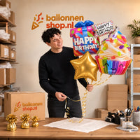 Jesse houdt Happy Birthday XL Tros vast in de warme werkplaats van Ballonnenshop.nl.