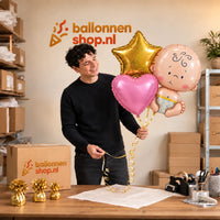 Jesse houdt Baby Trosje Helium Ballonnen Roze vast in de warme werkplaats van Ballonnenshop.nl.
