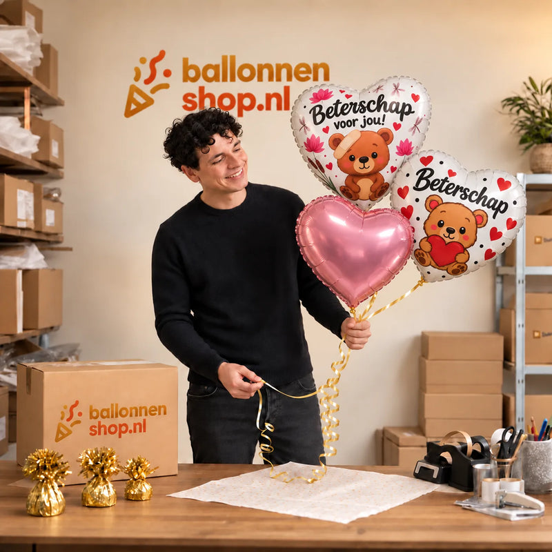 Jesse houdt Beterschap Voor Jou! Trosje Roze vast in de warme werkplaats van Ballonnenshop.nl.