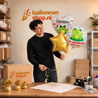 Jesse houdt Opkikker Voor Jou Trosje vast in de warme werkplaats van Ballonnenshop.nl.