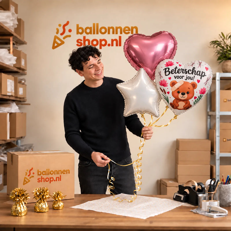 Jesse houdt Beterschap Trosje Ballonnen vast in de warme werkplaats van Ballonnenshop.nl.