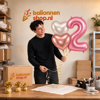 Jesse houdt 2 Jaar Mat Roze Hartjes Tros vast in de warme werkplaats van Ballonnenshop.nl.