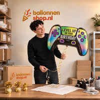 Jesse houdt de Vivid Game Controller Birthday XL vast in de warme inpakruimte van Ballonnenshop.nl.