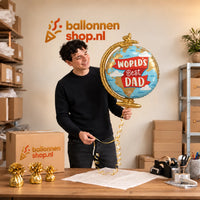 Jesse houdt de World's Best Dad Wereldbol Ballon vast in de warme inpakruimte van Ballonnenshop.nl.
