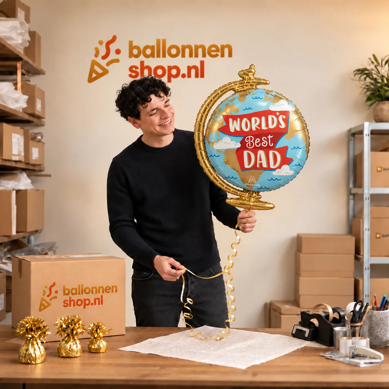 Jesse houdt de World's Best Dad Wereldbol Ballon vast in de warme inpakruimte van Ballonnenshop.nl.