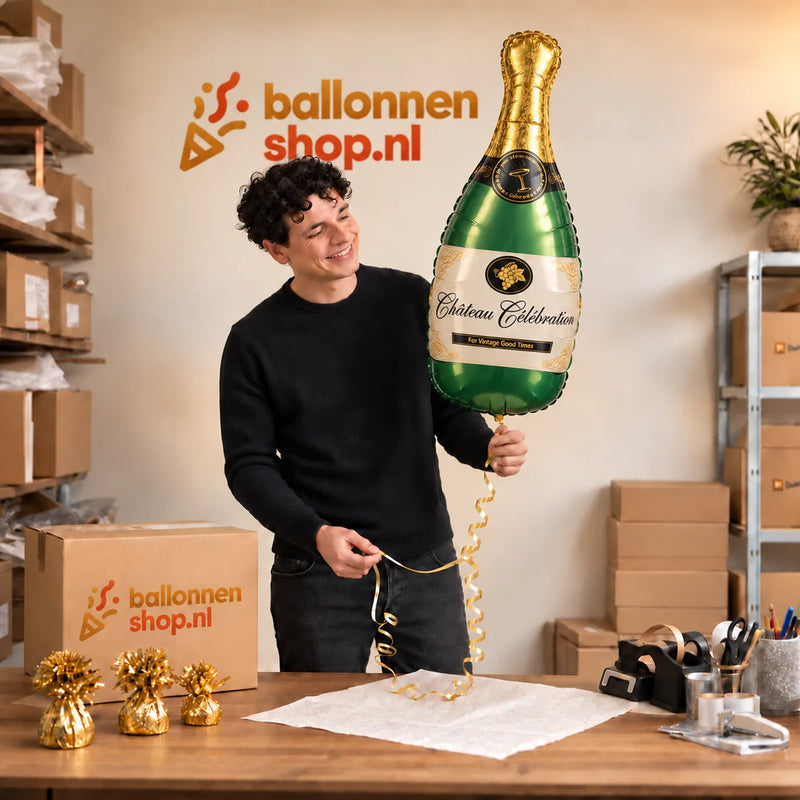 Jesse houdt de Champagne Fles Helium XL Ballon vast in de warme inpakruimte van Ballonnenshop.nl.