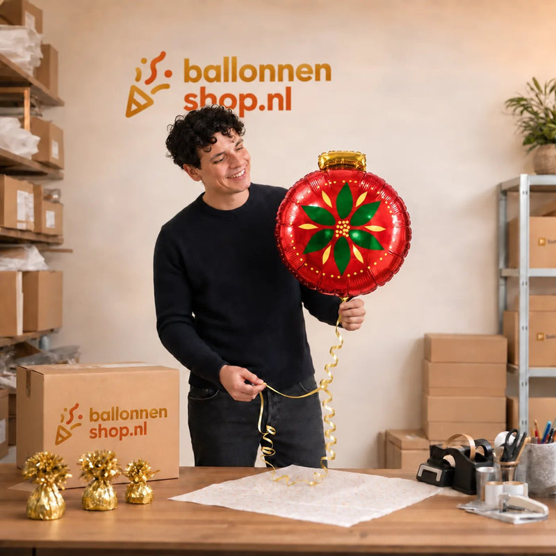 Jesse houdt de Kerstbal Helium Ballon vast in de warme werkplaats van Ballonnenshop.nl.