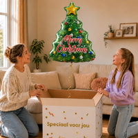 Kerstboom Merry Christmas XL – uitpakmoment met moeder en meisje in een warme woonkamer – Ballonnenshop.nl