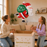 Kerstman Ho Ho Ho! XL Ballon – uitpakmoment met moeder en meisje in een warme woonkamer – Ballonnenshop.nl