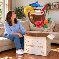 Een vrouw kijkt blij naar Kokosnoot Cocktail Pina Colada XL boven een grote Speciaal voor jou-doos in een warme woonkamer.