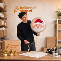 Jesse houdt de Lachende Kerstman Helium Ballon vast in de warme werkplaats van Ballonnenshop.nl.
