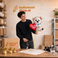 Jesse houdt de Love You Hondje Ballon vast in de warme werkplaats van Ballonnenshop.nl.