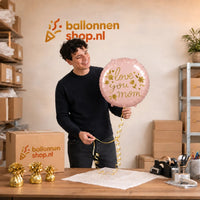 Jesse houdt de Love You Mom Helium Ballon vast in de warme werkplaats van Ballonnenshop.nl.