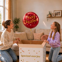 Moeder en meisje bij een bordeauxrode Merry Christmas heliumballon van 46 cm boven de cadeaudoos.