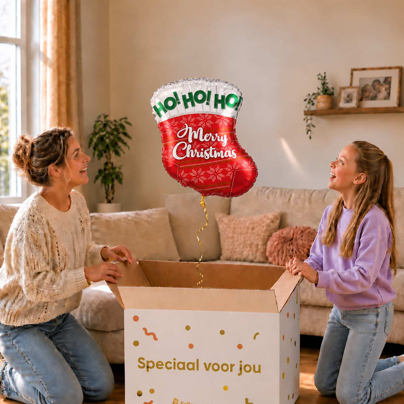 Moeder en meisje bekijken een kerstballon in de vorm van een rode kerstsok van 45 cm boven de cadeaudoos.