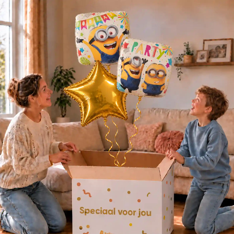 Minion Verjaardags Trosje Geel/Wit/Goud: moeder en zoon pakken het heliumgevulde ballonnentrosje uit een Speciaal voor jou-doos, met natuurlijk gekrulde gouden linten.