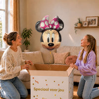 Moeder en meisje bekijken een Minnie Mouse-ballon van 66 cm met gouden lint boven de geopende cadeaudoos ‘Speciaal voor jou’.