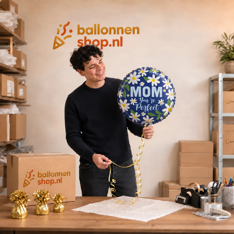 Jesse houdt de Mom You're Perfect Helium Ballon vast in de warme werkplaats van Ballonnenshop.nl.