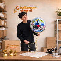Jesse houdt de Motor Rijbewijs Geslaagd Ballon vast in de warme werkplaats van Ballonnenshop.nl.