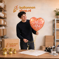 Jesse houdt de Mr & Mrs Hart Helium Ballon vast in de warme werkplaats van Ballonnenshop.nl.