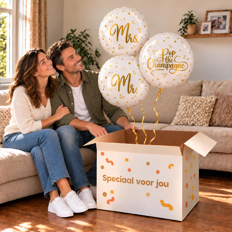 Een feestelijk huwelijksmoment met Mr & Mrs Pop The Campagne Trosje boven een open Speciaal voor jou-doos in een warme woonkamer.