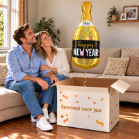 Een volwassen stel kijkt blij naar New Year Champagne XL Ballon boven een grote Speciaal voor jou-doos in een warme woonkamer.