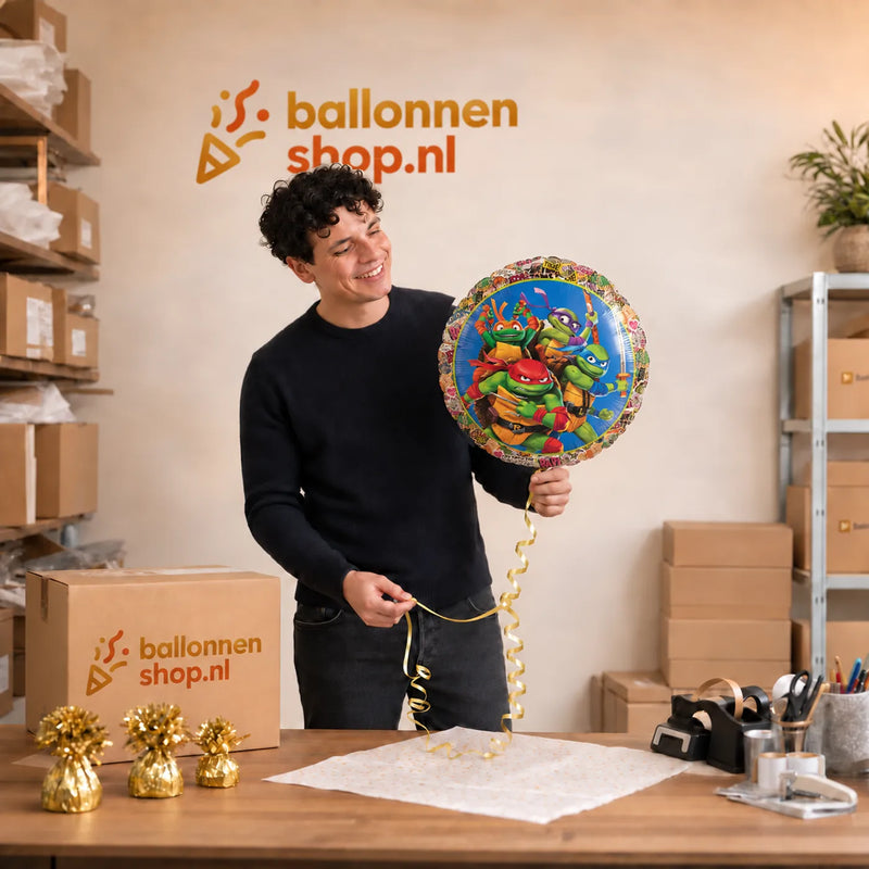 Jesse houdt de Ninja Turtle Helium Ballon vast in de warme werkplaats van Ballonnenshop.nl.