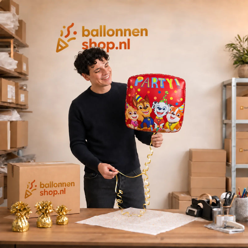 Jesse houdt de Paw Patrol Party Ballon Rood vast in de warme werkplaats van Ballonnenshop.nl.