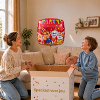 Moeder en jongen bekijken de rode Paw Patrol Party ballon van 46 cm bij het uitpakken van de cadeaudoos.