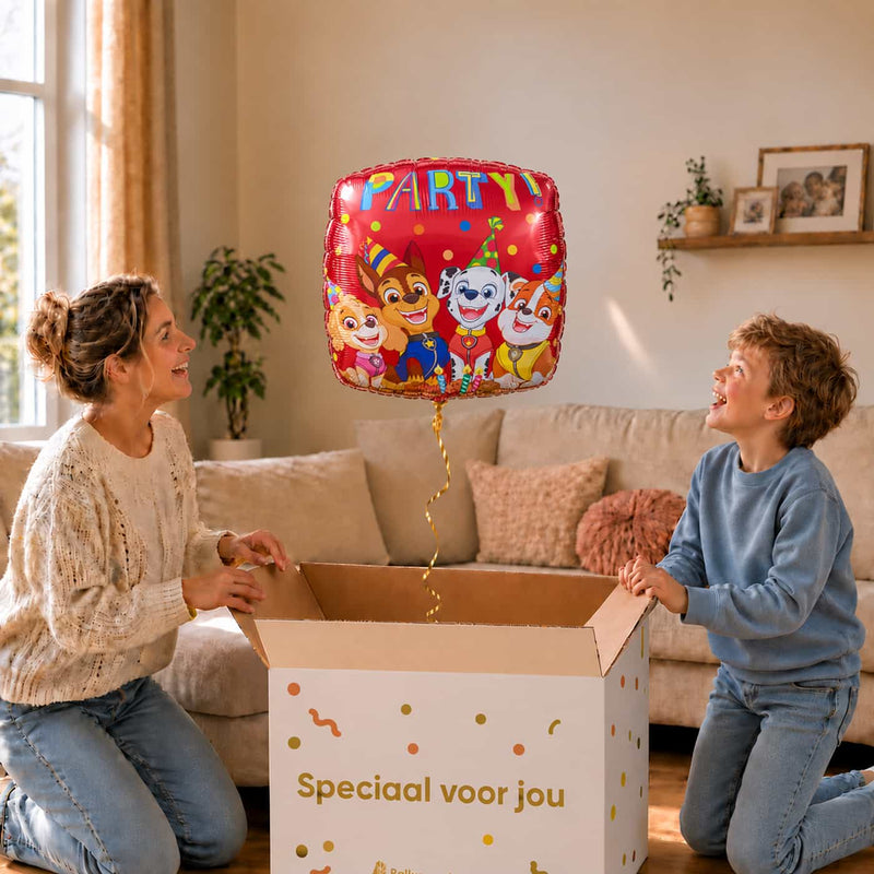 Moeder en jongen bekijken de rode Paw Patrol Party ballon van 46 cm bij het uitpakken van de cadeaudoos.