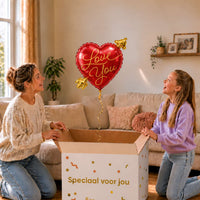 Moeder en dochter bekijken een rode Love You hartballon van 45 cm met gouden pijl boven de cadeaudoos.