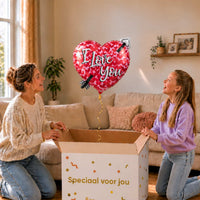 Moeder en meisje kijken naar de I Love You hartballon met pijl van 45 cm boven de cadeaudoos.