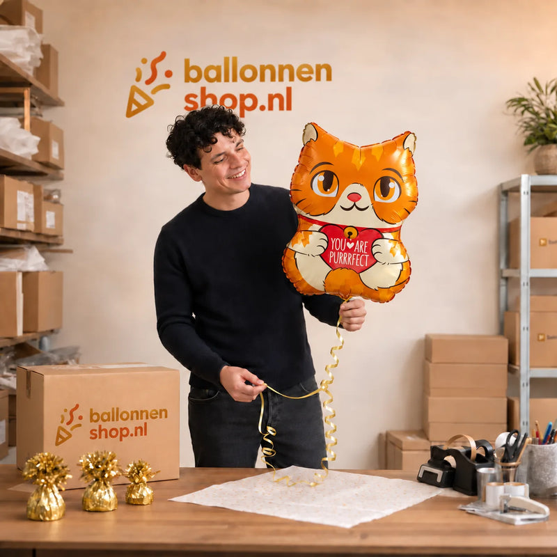 Jesse houdt de Poes You are Purrrfect Ballon vast in de warme werkplaats van Ballonnenshop.nl.