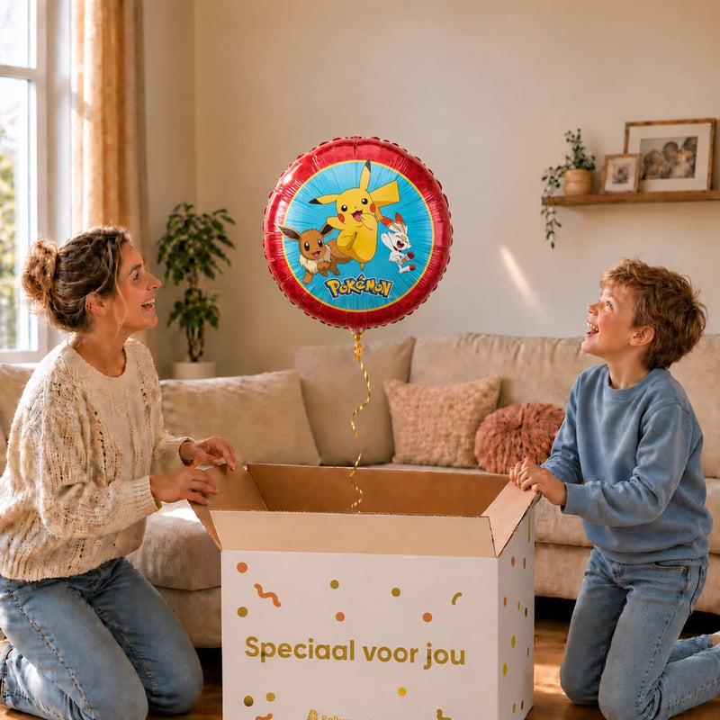 Moeder en jongen pakken de Pokémon ballon van 46 cm met Pikachu, Eevee en Scorbunny uit de cadeaudoos.