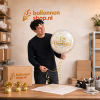 Jesse houdt de Pop The Champagne Helium Ballon vast in de warme werkplaats van Ballonnenshop.nl.