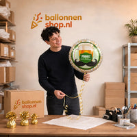 Jesse houdt de Proost Van Harte Helium Ballon vast in de warme werkplaats van Ballonnenshop.nl.