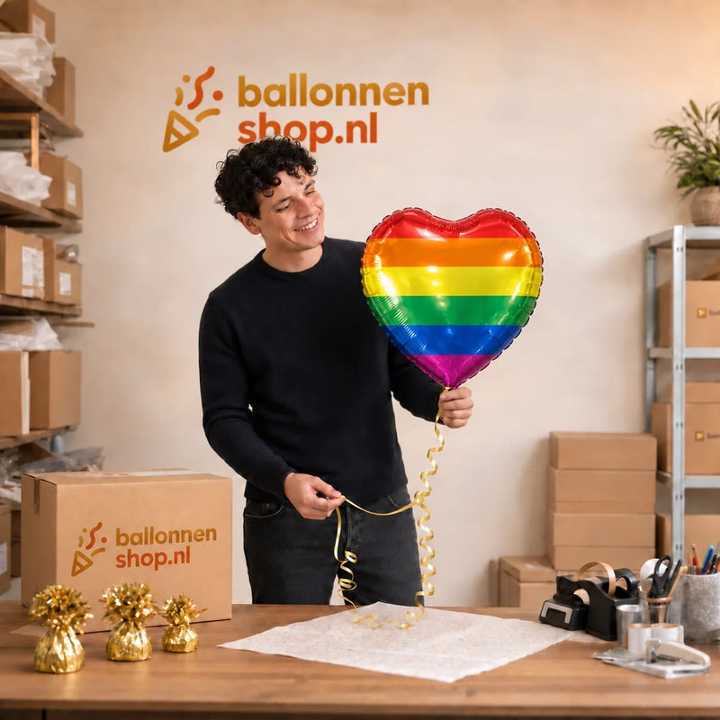 Jesse houdt de Regenboog Hart Ballon vast in de warme werkplaats van Ballonnenshop.nl.