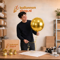 Jesse houdt de Ronde Helium Ballon Goud vast in de warme werkplaats van Ballonnenshop.nl.