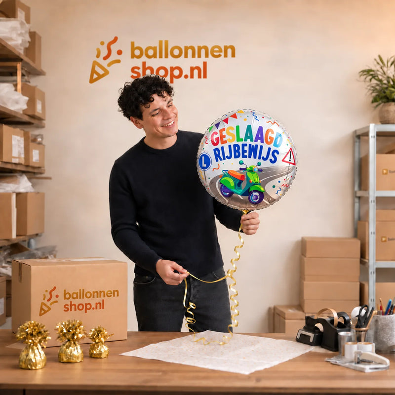 Jesse houdt de Scooter Rijbewijs Geslaagd Ballon vast in de warme werkplaats van Ballonnenshop.nl.