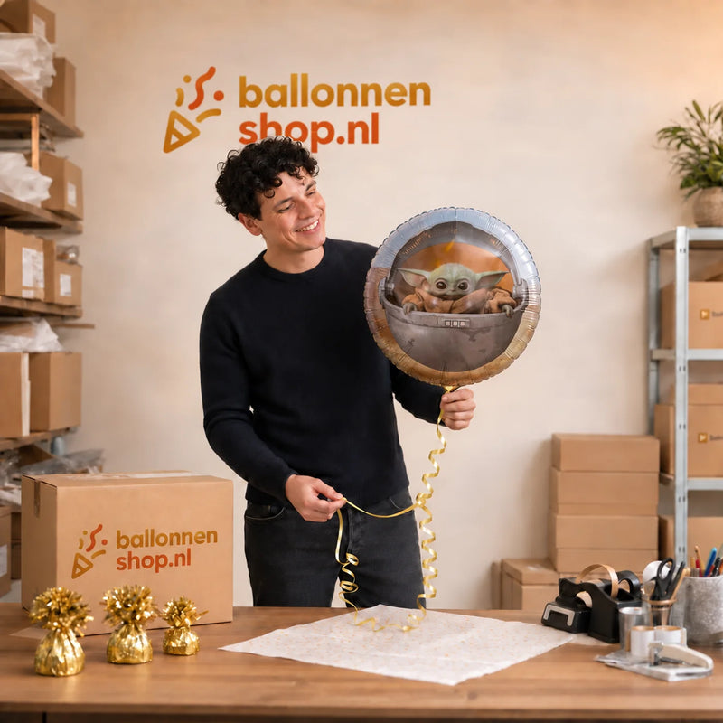 Jesse houdt de Star Wars Baby Yoda Helium Ballon vast in de warme werkplaats van Ballonnenshop.nl.