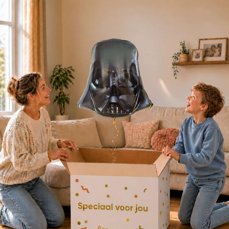 Moeder en jongen bekijken een Darth Vader-ballon van 63 cm met gouden lint boven de geopende cadeaudoos ‘Speciaal voor jou’.