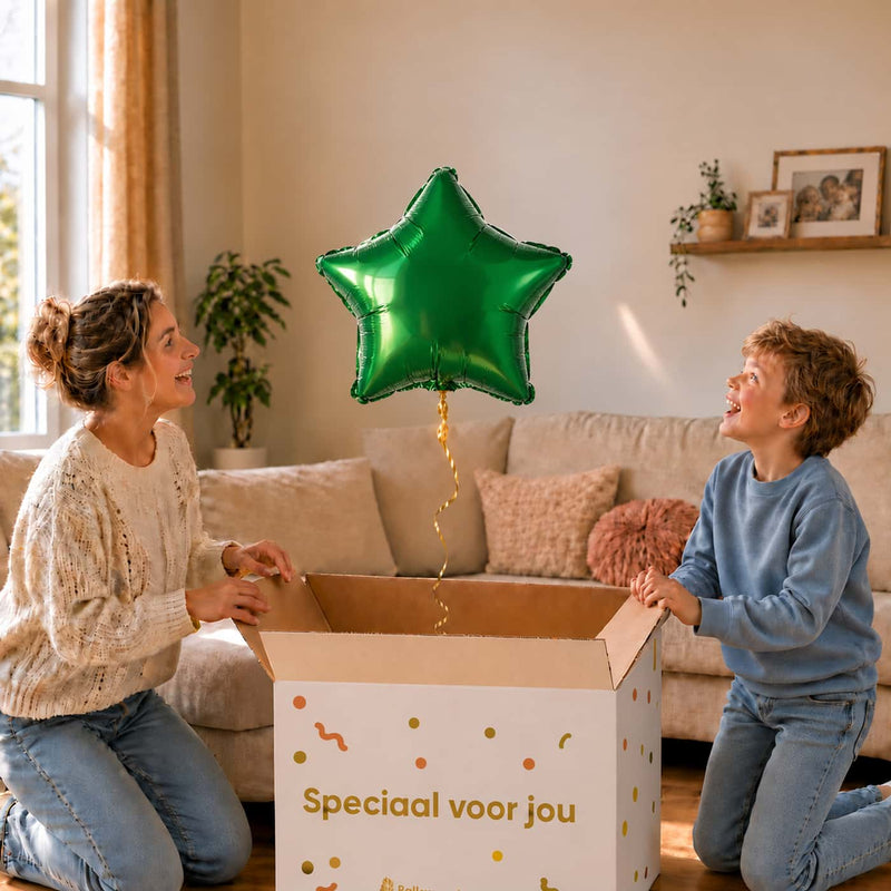 Jongen en moeder bekijken een groene stervormige heliumballon van 46 cm boven de open cadeaudoos.
