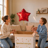 Moeder en jongen pakken een rode sterballon van 46 cm uit de cadeaudoos.
